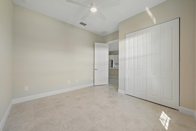 unfurnished bedroom with baseboards, a closet, a ceiling fan, and light tile patterned floors