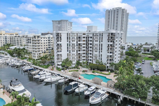 drone / aerial view of a nearby body of water, a pool, apartment complex / building, and numerous boat docks