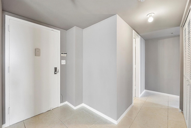 corridor featuring light tile patterned floors and baseboards