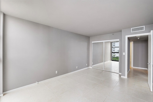 unfurnished bedroom with light tile patterned flooring, a closet, and baseboards