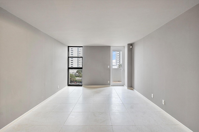 empty room with light tile patterned flooring and baseboards