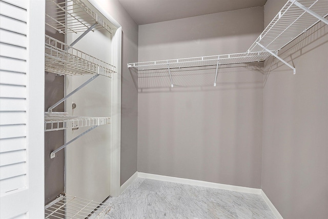walk in closet featuring marble look tile flooring