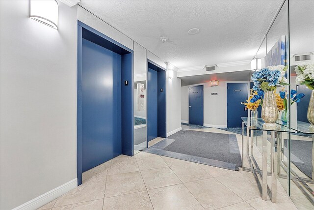 hallway with elevator, a textured ceiling, tile patterned flooring, baseboards, and ornamental molding