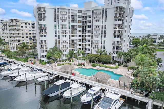view of apartment building / complex with uncovered parking, a water view, and a community pool