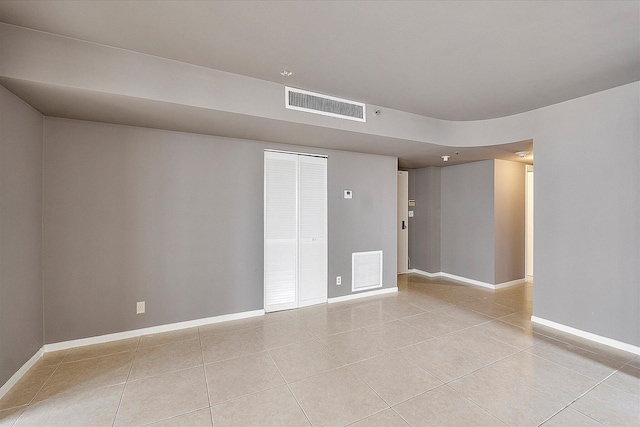 spare room with light tile patterned flooring and baseboards