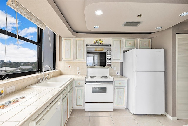 kitchen with white appliances, tile counters, a sink, light tile patterned floors, and recessed lighting