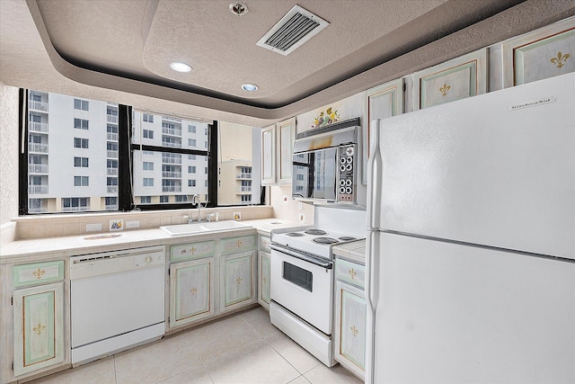 kitchen featuring white appliances, a sink, a textured ceiling, light tile patterned flooring, and tile counters