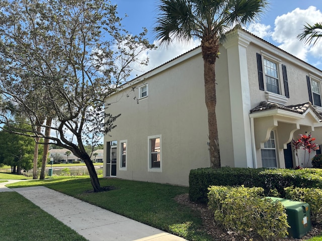 view of home's exterior featuring stucco siding, a yard, and a tile roof