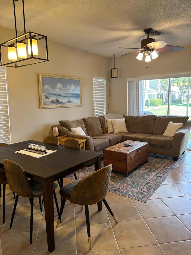 living room featuring ceiling fan, light tile patterned flooring, and a textured ceiling