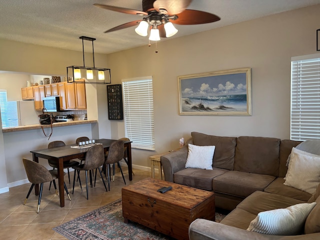living area featuring a ceiling fan, baseboards, and light tile patterned floors