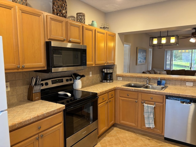 kitchen featuring appliances with stainless steel finishes, a sink, tasteful backsplash, and ceiling fan