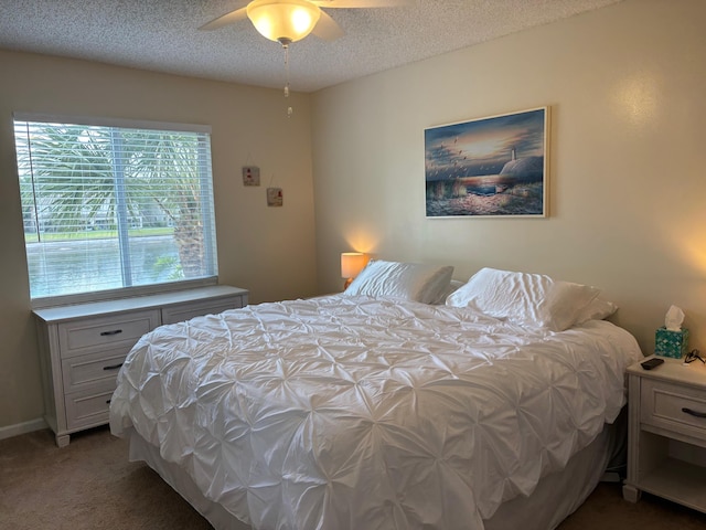 bedroom featuring light colored carpet, a textured ceiling, and a ceiling fan