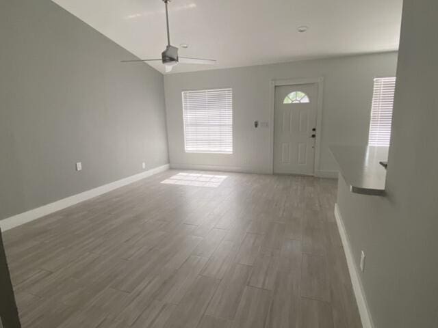 foyer entrance featuring baseboards, wood finished floors, and a ceiling fan
