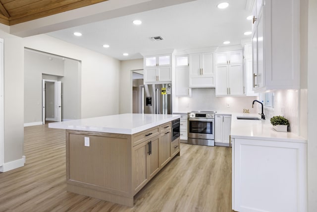 3333 Southern Cay Dr, Jupiter, FL 33477 - kitchen with appliances with stainless steel finishes, a sink, light wood-type flooring, light countertops, and a kitchen island