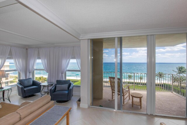 3230 S Ocean Blvd Unit D511, Palm Beach, FL 33480 - living area with a water view, ornamental molding, a textured ceiling, and baseboards