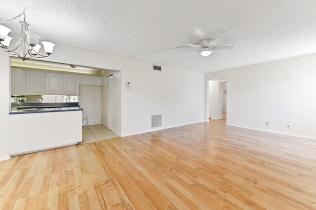 302 Knotty Pine Cir Unit D-1, Greenacres, FL 33463 - unfurnished living room with light wood-type flooring, ceiling fan, a chandelier, a textured ceiling, and baseboards