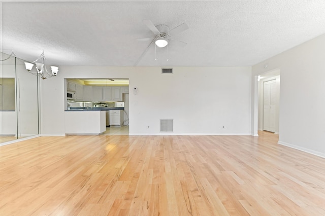 302 Knotty Pine Cir Unit D-1, Greenacres, FL 33463 - unfurnished living room featuring light wood-style flooring, a ceiling fan, a textured ceiling, a chandelier, and baseboards