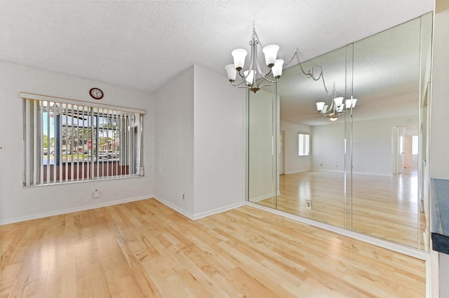 302 Knotty Pine Cir Unit D-1, Greenacres, FL 33463 - unfurnished room featuring a chandelier, wood finished floors, a textured ceiling, and baseboards