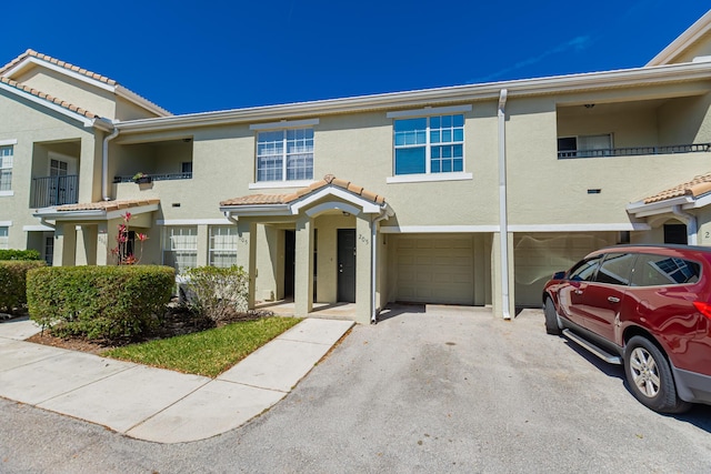 166 SW Peacock Blvd Unit 34-205, Port Saint Lucie, FL 34986 - view of property featuring stucco siding, driveway, a garage, and a tiled roof