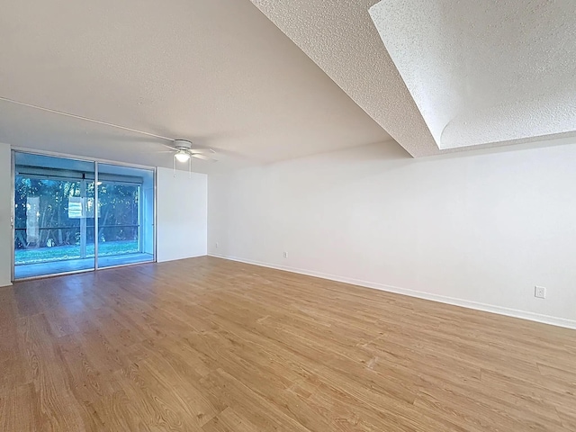 empty room featuring a textured ceiling, wood finished floors, ceiling fan, and baseboards