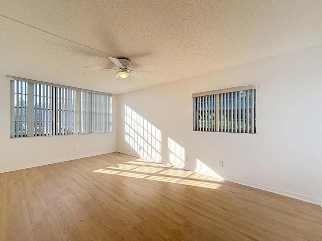 unfurnished room featuring ceiling fan, wood finished floors, baseboards, and a textured ceiling