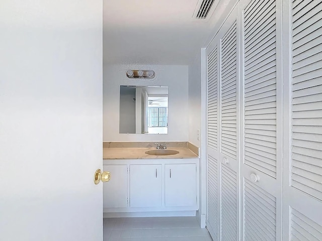bathroom with tile patterned flooring, vanity, and a closet