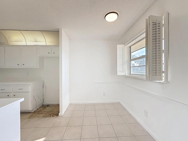 kitchen featuring a textured ceiling, light countertops, baseboards, and light tile patterned flooring