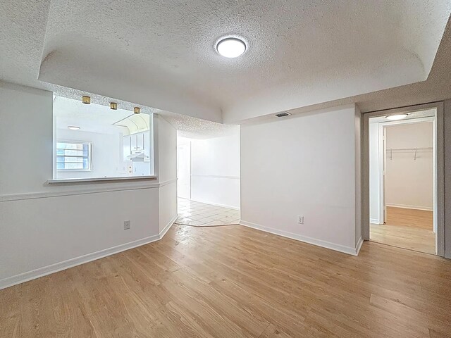 spare room featuring a textured ceiling, wood finished floors, ceiling fan, and baseboards