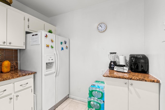 2538 Boundbrook Dr S Unit 140, West Palm Beach, FL 33406 - kitchen with white fridge with ice dispenser, light tile patterned flooring, tasteful backsplash, white cabinetry, and dark stone counters