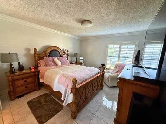 3790 Silver Lace Ln, Boynton Beach, FL 33436 - bedroom featuring crown molding, light tile patterned flooring, and a textured ceiling