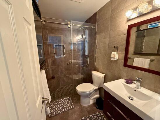 3790 Silver Lace Ln, Boynton Beach, FL 33436 - full bathroom with tile walls, a stall shower, toilet, and vanity