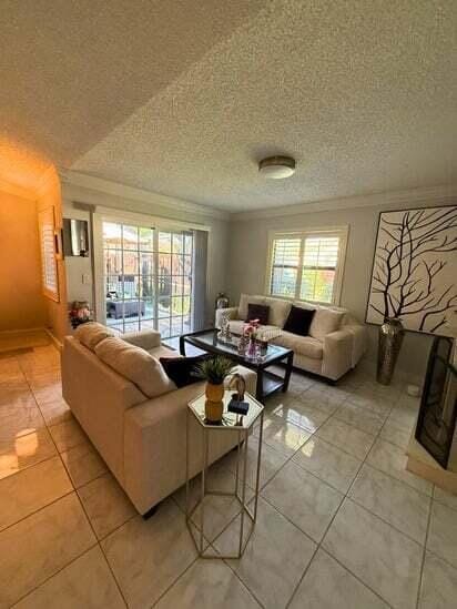 3790 Silver Lace Ln, Boynton Beach, FL 33436 - living room featuring crown molding, light tile patterned floors, and a textured ceiling