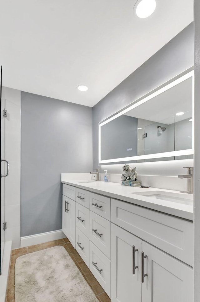 full bathroom featuring a stall shower, double vanity, tile patterned flooring, and baseboards