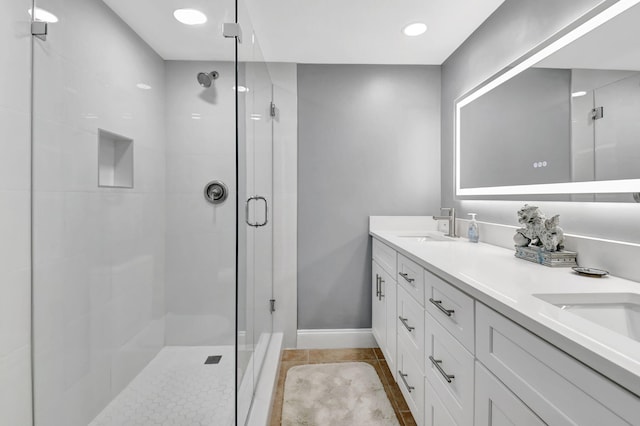 bathroom featuring a stall shower, baseboards, double vanity, tile patterned floors, and recessed lighting