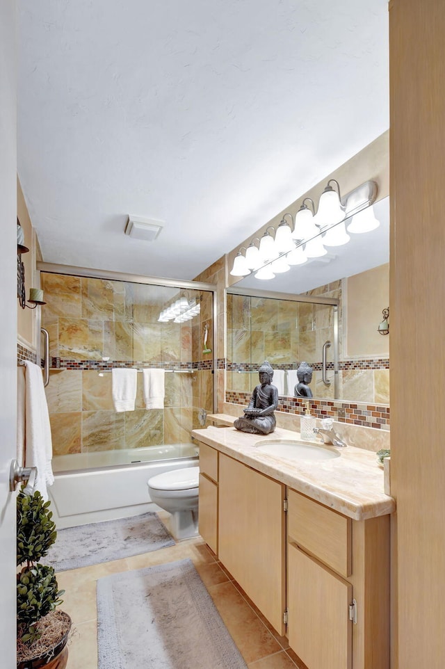 full bathroom with decorative backsplash, vanity, bath / shower combo with glass door, toilet, and tile walls
