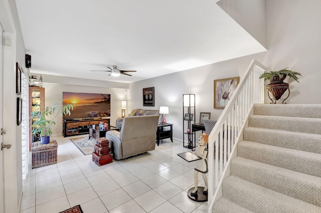 living area featuring stairway, a ceiling fan, light tile patterned floors, and baseboards