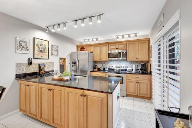 kitchen featuring appliances with stainless steel finishes, light tile patterned floors, a peninsula, a sink, and tasteful backsplash