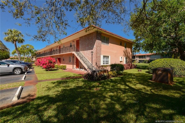 1925 SW Palm City Rd Unit C, Stuart, FL 34994 - view of home's exterior with stucco siding, stairway, a lawn, and uncovered parking