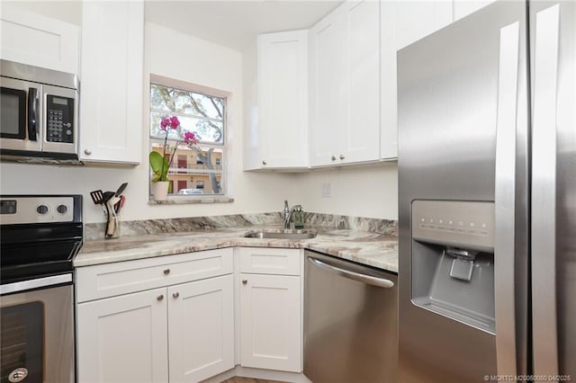 1925 SW Palm City Rd Unit C, Stuart, FL 34994 - kitchen with appliances with stainless steel finishes, a sink, white cabinets, and light stone counters