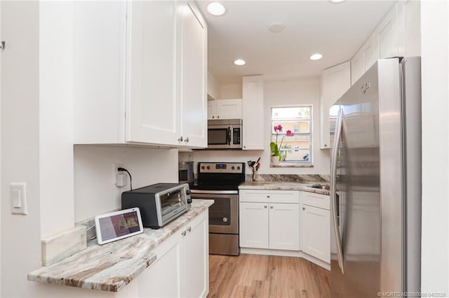 1925 SW Palm City Rd Unit C, Stuart, FL 34994 - kitchen featuring appliances with stainless steel finishes, white cabinetry, light wood-style floors, and recessed lighting