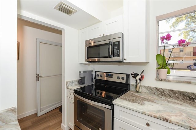 1925 SW Palm City Rd Unit C, Stuart, FL 34994 - kitchen with stainless steel appliances, white cabinetry, light wood-style flooring, light stone countertops, and baseboards