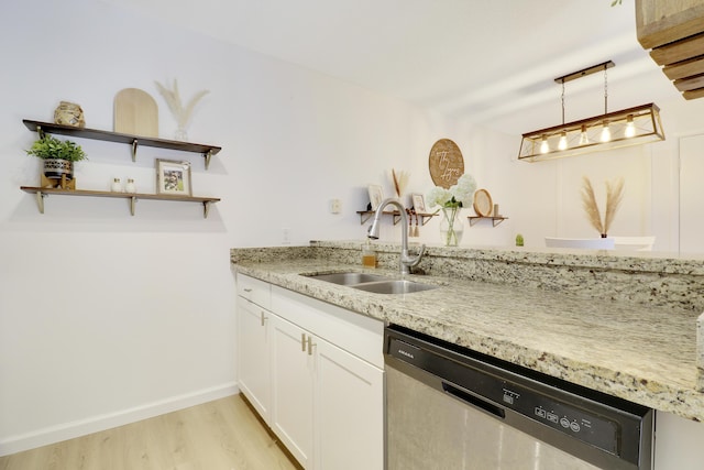 kitchen with stainless steel dishwasher, a sink, light wood-style flooring, light stone counters, and white cabinetry