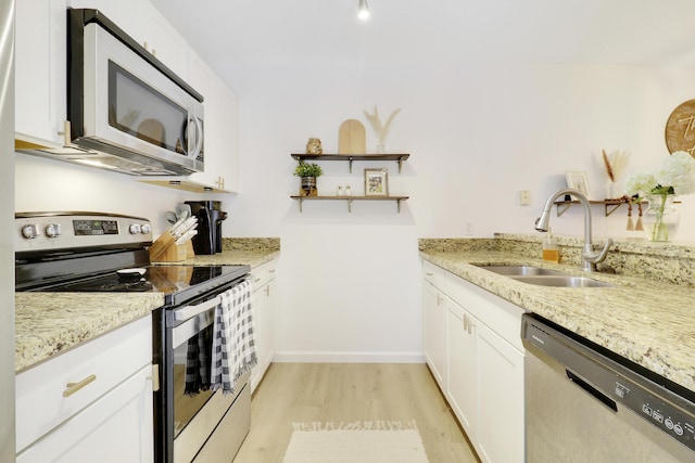 kitchen featuring stainless steel appliances, a sink, light wood-style floors, open shelves, and white cabinets