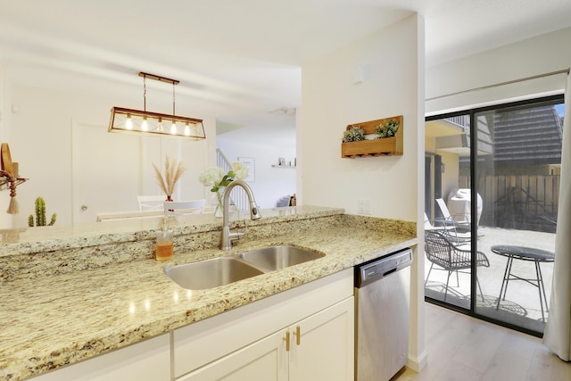 kitchen with stainless steel dishwasher, a sink, light stone countertops, and decorative light fixtures