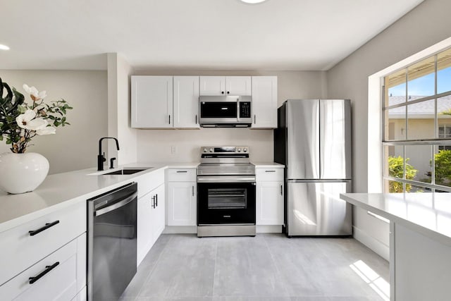 kitchen featuring appliances with stainless steel finishes, a sink, light countertops, and white cabinets