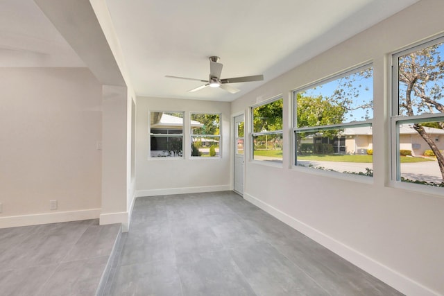 empty room with baseboards, a ceiling fan, and concrete floors