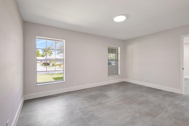 unfurnished room with baseboards and concrete floors