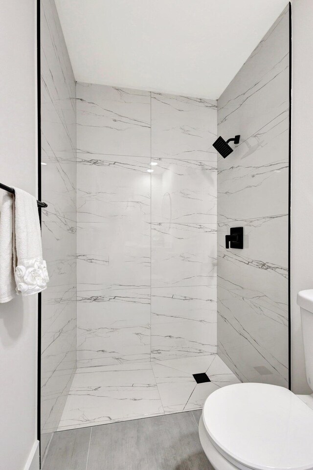 full bath featuring toilet and a marble finish shower