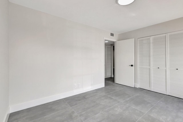 unfurnished bedroom with baseboards, concrete floors, and a closet