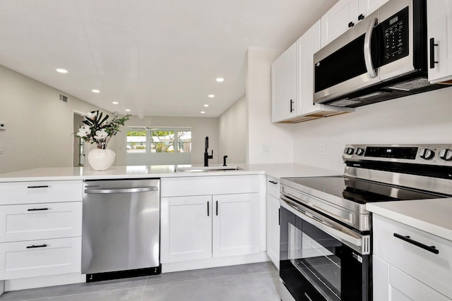 kitchen with appliances with stainless steel finishes, a sink, light countertops, recessed lighting, and white cabinets